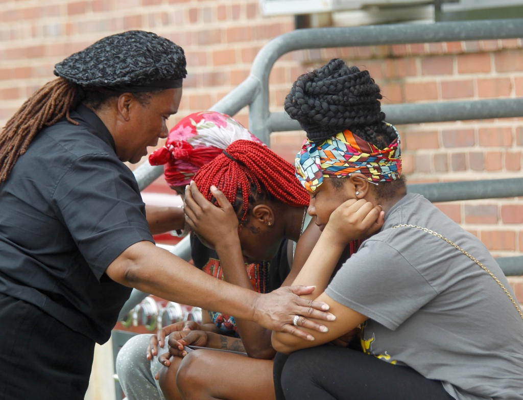 Mourners grieve after two people were shot dead and 28 wounded at a block party in Baltimore.