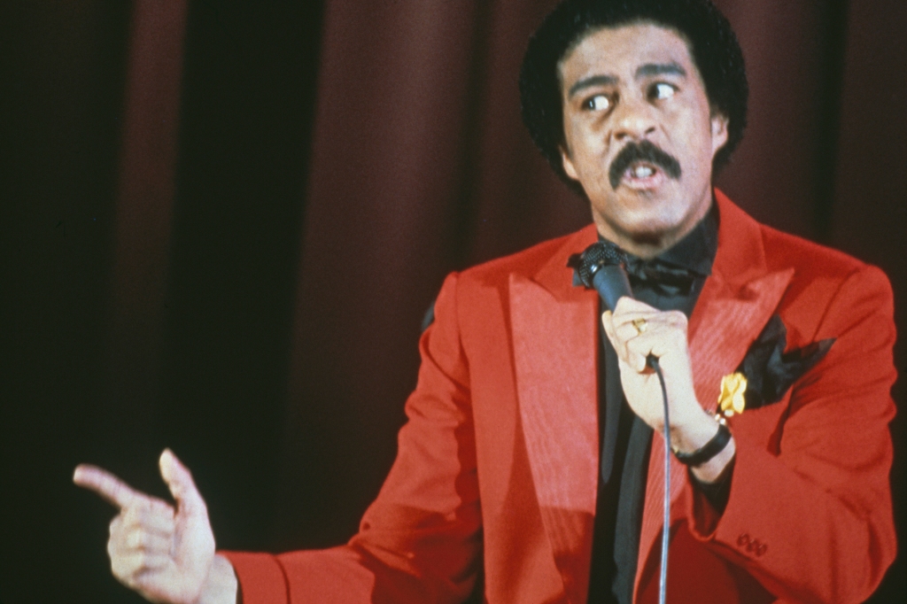 Richard Pryor onstage in a red jacket in 1977.