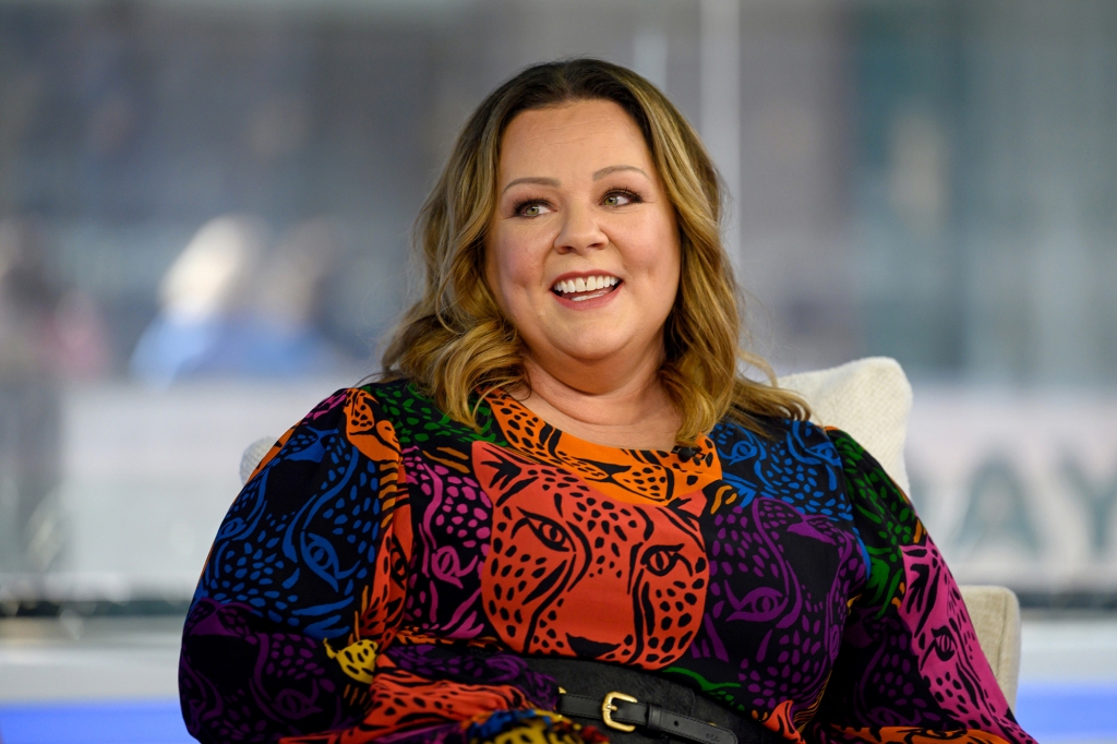 Melissa McCarthy smiles in a multi colored dress.
